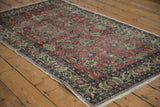 Distressed cherry red Oushak rug field and beige border with scrolling tendrils.