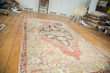 Faded cinnabar red field, oversized scalloped medallion, and charcoal floral details on a distressed Oushak rug.