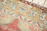 Faded cinnabar red and saffron yellow floral patterns on a distressed vintage Oushak rug.