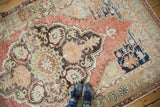Distressed vintage Oushak carpet showing scalloped floral medallion in faded cinnabar red and charcoal.