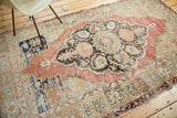 Vintage Oushak rug's distressed field, revealing faded cinnabar red, navy blue, and sand abrash.