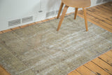 Distressed Oushak rug with faded octagonal medallion and geometric border in muted earth tones.