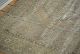 Distressed vintage Oushak rug texture, showing muted earth tones and geometric border pattern.