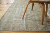 Fringed end of distressed vintage Oushak rug with muted geometric patterns.