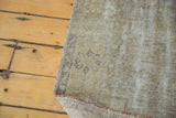 Close-up of distressed vintage Oushak rug pile with secured side in muted earth tones.