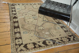 Distressed vintage Oushak rug corner with dark brown border, ivory field, and faded blue motifs.