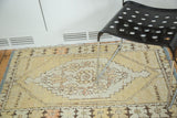 Faded saffron yellow and beige distressed vintage Oushak rug with floral medallion.