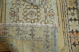 Reverse view of the hand-knotted vintage Oushak rug showing secured end and distressed pile.