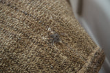 Coarse speckled goat hair texture of vintage grainbag, showcasing storied repairs in natural tones.