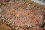 Corner detail of vintage Turkish Oushak rug with tangerine, eggplant, and rust motifs, multicolored selvedge.