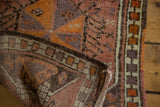 Curled back view of the Oushak rug, showing its brown foundation and multicolored selvedge.
