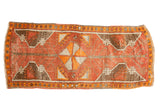 Distressed vintage Oushak runner rug with faded red, orange, and brown pinwheel medallion.
