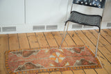 Distressed vintage Oushak runner with tangerine orange pinwheel and madder red field.