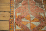 Distressed vintage Oushak rug's geometric patterns, tangerine orange border, and original side selvedge detail.