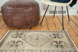 Distressed vintage Oushak rug mat; beige field, stepped medallion, and floral corner design.