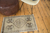 Distressed vintage Oushak rug mat corner with beige, bronze, and burgundy geometric motifs.