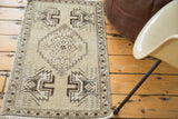 Distressed Oushak rug mat corner, beige field, deep burgundy border, and planter motif.
