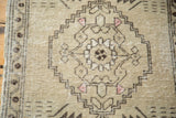 Distressed Oushak rug close-up: textured stepped medallion, chocolate bronze, faded burgundy.