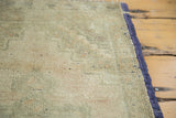 Textured hand-knotted Oushak rug pile showing faded beige, green, peach, and original dark selvedge.