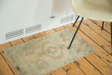 Faded ivory vintage Oushak rug, oblong medallion, and germinating flower motifs.