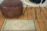 Distressed vintage Oushak rug corner showing subtle beige, sea foam green, and bronze border.