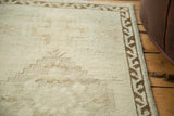 Distressed texture of a vintage Oushak rug corner with a bronze geometric border.