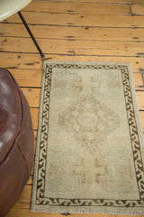 Corner detail of distressed vintage Oushak rug with subtle germinating planter motif and bronze border.