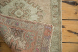 Vintage Oushak rug corner, showing soft green pile and hand-knotted pink-purple reverse.