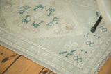 Vintage Oushak rug corner with soft green border, beige motifs, and intact selvedge.