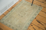 Corner of vintage Oushak rug with faded pistachio border, slate blue motifs, and side selvedge.