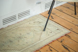 Corner of vintage Oushak rug with subtle floral bouquets, beige field, and burnt orange selvedge.