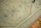 Oushak rug corner showcasing beige field, sage green outlines, chocolate brown motifs, and red selvedge.