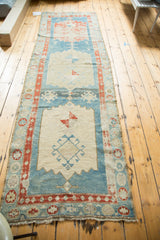 Geometric designs within a light medallion and distressed aqua blue field on the antique runner.