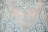 Close-up of vintage Oushak rug runner's distressed pile, pale blush field, aqua, and ivory patterns.