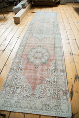 Distressed corner of a vintage Oushak runner, showing pale blush, aqua, and ivory motifs.