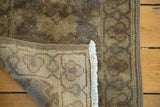Hand-knotted vintage European rug corner, showing brown geometric pile, woven beige foundation, and fringe.