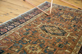 Faded brick red field, teal geometric patterns, and floral border of the vintage Karaja rug.