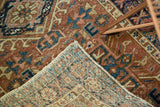 Folded corner of vintage Karaja rug shows hand-knotted foundation and faded brick red, teal pattern.
