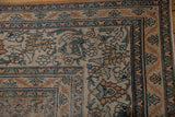 Distressed Antique Khorassan carpet corner detail: faded rust, blue floral patterns, exposed foundation.