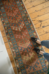 Geometric arrowhead, floral, and diamond patterns on Heriz runner in brick red, sky blue.
