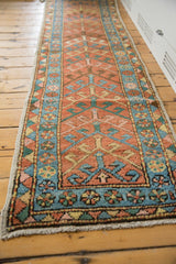 Hand-knotted antique Heriz runner corner: brick red pile, sky blue floral-geometric borders, and fringe.
