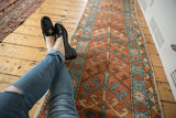 Antique Heriz runner: central geometric arrowhead, simplistic floral border in brick red, sky blue, green.
