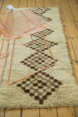 Thick, plush pile of a geometric Moroccan rug with ivory and coffee brown diamond checkered pattern.
