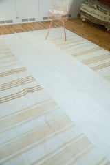 Vintage patchwork kilim carpet with plain ivory center and varied beige stripes.