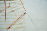 Patchwork seam of vintage kilim, plain ivory field meets varied sand stripes, subtle staining.