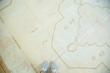 Vintage Dhurrie carpet detail: pale peach geometric Serapi-inspired motifs, coffee outlines, and sneakers.