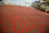 Angled view of modern Turkish Kilim rug with black cherry red and charcoal endless knot pattern.
