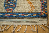 Plush pile with blue and orange pattern, secured flatwoven edge, and braided ivory fringe.