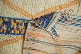 Hand-knotted Moroccan runner showing plush ivory pile, speckled blue border, and striped woven back.