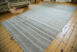 Varying thickness horizontal stripes on speckled beige vintage flatweave carpet in platinum and silver.
